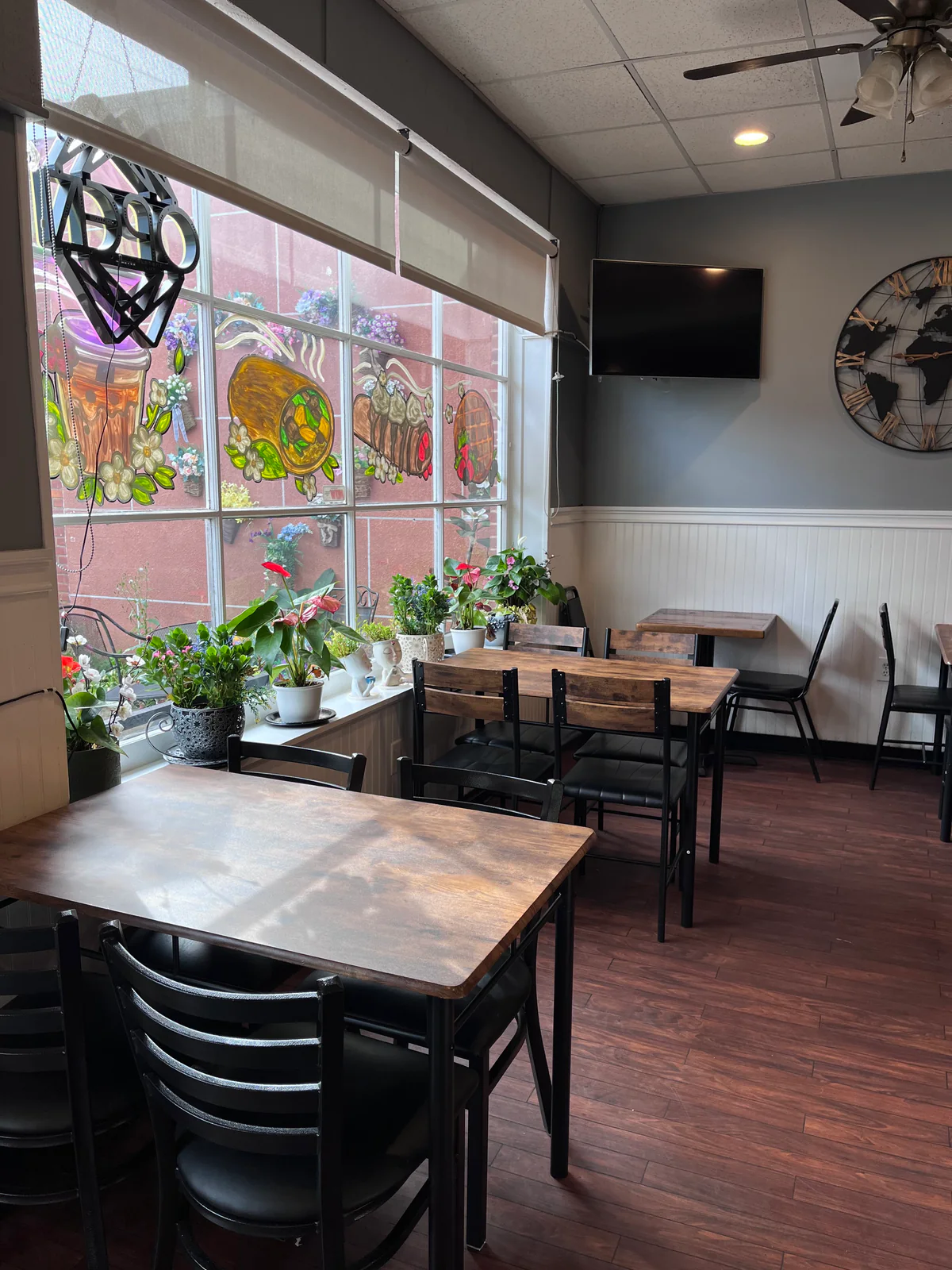 Café dining area with wooden tables and plants by painted windows